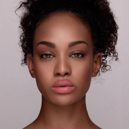 Model mit MoniAmori Extra-LipStay MM034 Dusty Rose: Frau mit lockigem dunklem Haar, intensiverem Lippenmakeup in sattem Dusty Rose, natürliches Porträt vor grauem Hintergrund.