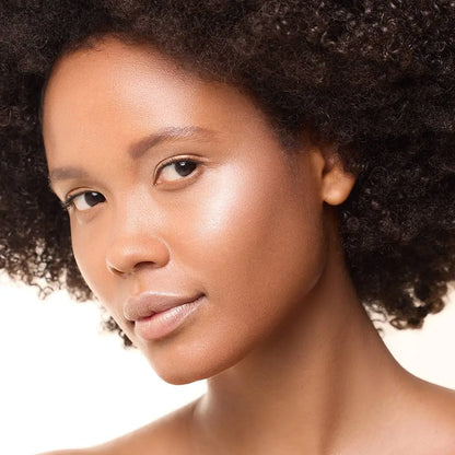 Model mit MoniAmori Light & Go Highlighter Stick: Frau mit strahlendem Teint und leuchtenden Akzenten auf den Wangenknochen, natürliches Make-up mit Glow-Effekt, leicht seitliche Porträtaufnahme.
