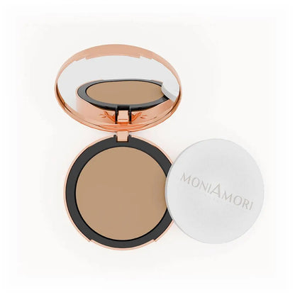 MoniAmori Solar Defence Compact Foundation MM006 Amaretto: Geöffnete roségoldene Puderdose mit Spiegel, die den warmen, mittleren Foundation-Ton zeigt, daneben der weiße Schwamm-Applikator mit MoniAmori-Logo, auf weißem Hintergrund.
