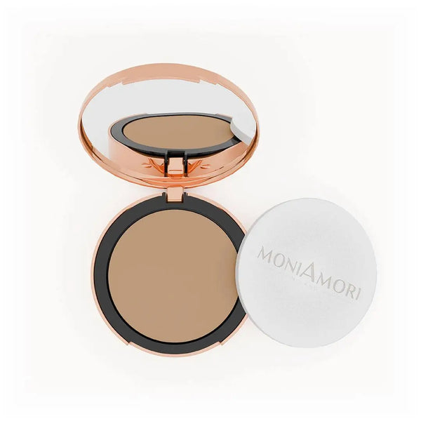 MoniAmori Solar Defence Compact Foundation MM006 Amaretto: Geöffnete roségoldene Puderdose mit Spiegel, die den warmen, mittleren Foundation-Ton zeigt, daneben der weiße Schwamm-Applikator mit MoniAmori-Logo, auf weißem Hintergrund.