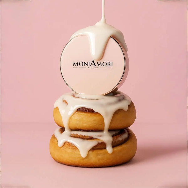 Kreative Produktinszenierung: Die geschlossene roségoldene Puderdose der MoniAmori Solar Defence Compact Foundation thront auf zwei echten Cinnamon Rolls (Zimtschnecken), über die weiße Glasur gegossen wird, passend zum Farbnamen "Cinnamon Roll".