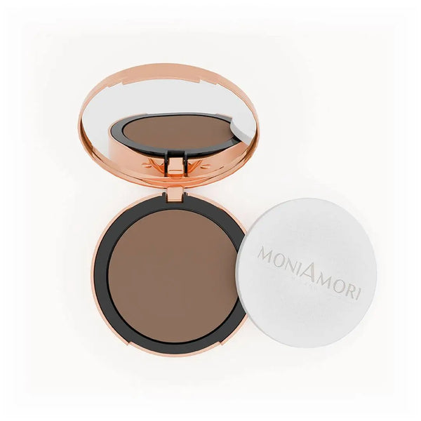 MoniAmori Solar Defence Compact Foundation MM009 Tiramisù: Geöffnete roségoldene Puderdose mit Spiegel, die den dunkelbraunen Foundation-Ton zeigt, daneben der weiße Schwamm-Applikator mit MoniAmori-Logo, auf weißem Hintergrund.